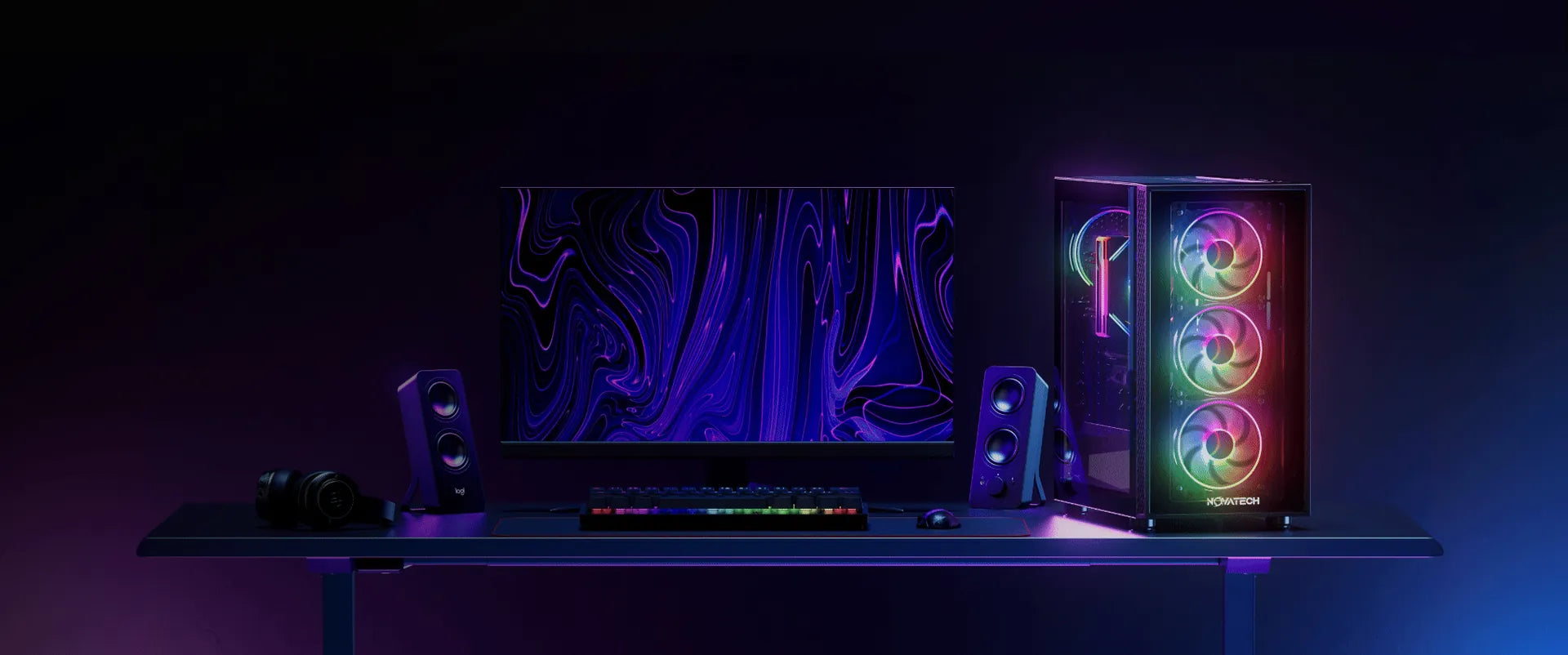 Novatech gaming PC with spinning RGB fans on a desk next to a monitor, keyboard and speakers
